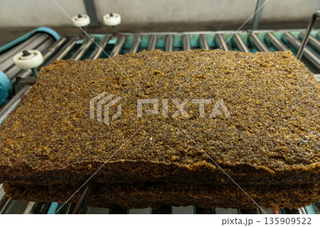 The close up image of the jagged brown natural raw rubber bales surface, lumpy solid block standard Thai rubber, in a factory. The close up image of the jagged brown natural raw rubber bales surface, lumpy solid block standard Thai rubber, in a factory. 135909522