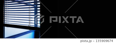 Wide interior banner image of horizontal window blinds with daylight and shadow lines, with large black copy space. Wide interior banner image of horizontal window blinds with daylight and shadow lines, with large black copy space. 135909674