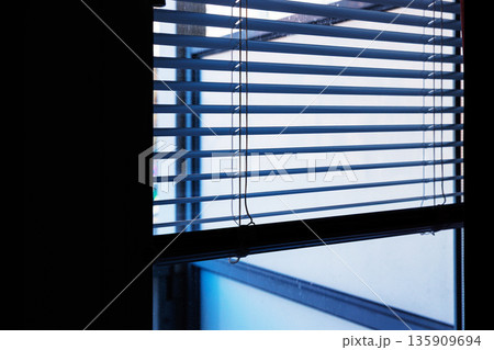 Interior view of horizontal window blinds with soft daylight and shadows, and a large dark area providing copy space. Interior view of horizontal window blinds with soft daylight and shadows, and a large dark area providing copy space. 135909694