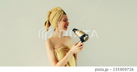 Portrait of happy smiling young woman drying wet hair in wrapped bath towel after taking a shower Portrait of happy smiling young woman drying wet hair in wrapped bath towel after taking a shower 135909716