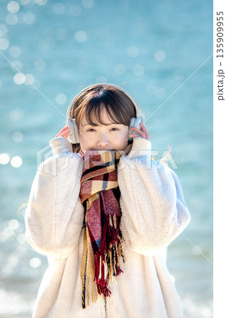 冬の海でヘッドホンで音楽を聴く若い女性 冬の海でヘッドホンで音楽を聴く若い女性 135909955