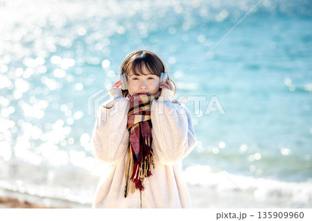 冬の海でヘッドホンで音楽を聴く若い女性 冬の海でヘッドホンで音楽を聴く若い女性 135909960