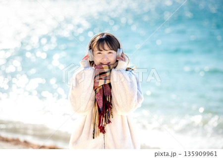 冬の海でヘッドホンで音楽を聴く若い女性 冬の海でヘッドホンで音楽を聴く若い女性 135909961
