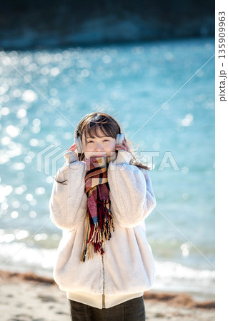 冬の海でヘッドホンで音楽を聴く若い女性 冬の海でヘッドホンで音楽を聴く若い女性 135909963