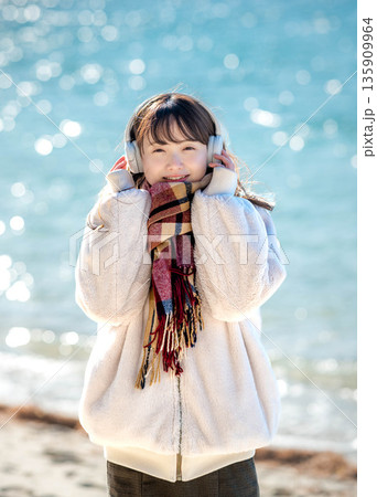 冬の海でヘッドホンで音楽を聴く若い女性 冬の海でヘッドホンで音楽を聴く若い女性 135909964