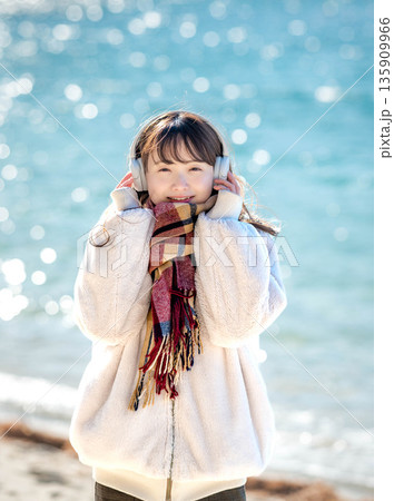 冬の海でヘッドホンで音楽を聴く若い女性 冬の海でヘッドホンで音楽を聴く若い女性 135909966