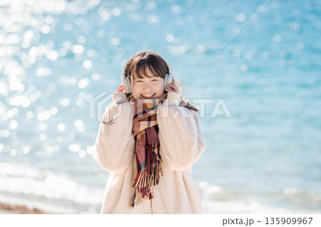 冬の海でヘッドホンで音楽を聴く若い女性 冬の海でヘッドホンで音楽を聴く若い女性 135909967