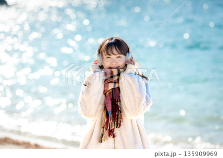 冬の海でヘッドホンで音楽を聴く若い女性 135909969