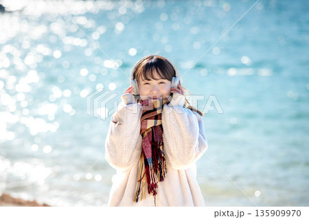 冬の海でヘッドホンで音楽を聴く若い女性 冬の海でヘッドホンで音楽を聴く若い女性 135909970