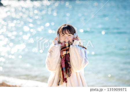 冬の海でヘッドホンで音楽を聴く若い女性 冬の海でヘッドホンで音楽を聴く若い女性 135909971