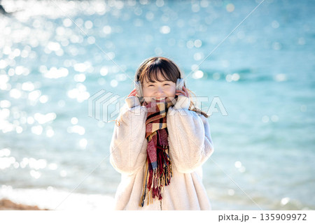冬の海でヘッドホンで音楽を聴く若い女性 135909972
