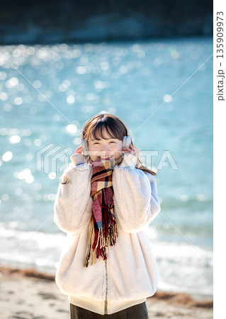 冬の海でヘッドホンで音楽を聴く若い女性 135909973