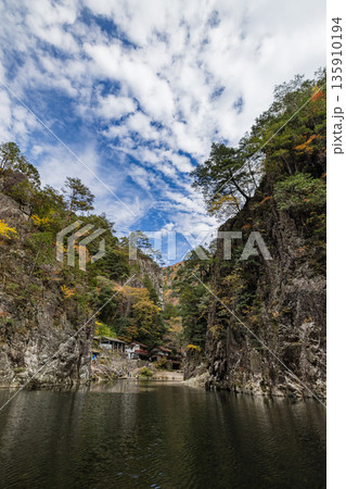 日本　広島県山県郡安芸太田町にある峡谷、三段峡の黒淵の渡し舟から眺める岩壁と紅葉した木々 135910194