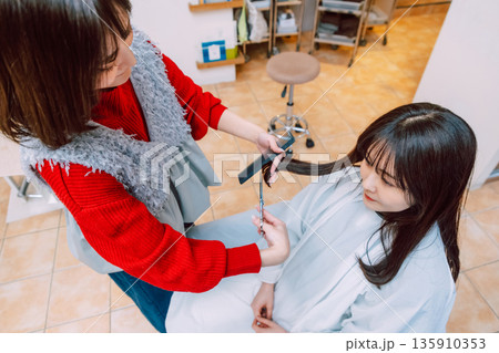 髪をカットする女性美容師　美容室  俯瞰 135910353