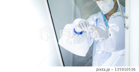 Hands of medical personnel holding a nasal swab ATK is collecting germs from a negative pressure operating room to determine whether or not we have coronavirus. 135910536