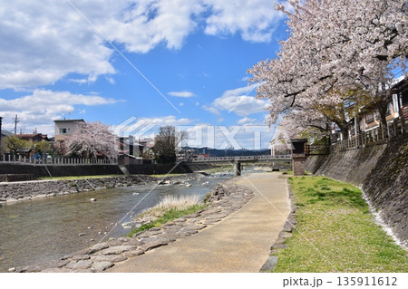 岐阜県の高山市 満開の桜と美しい青空 櫻山八幡宮の大鳥居と宮前橋 市街地を流れる宮川と周辺の街並み 岐阜県の高山市 満開の桜と美しい青空 櫻山八幡宮の大鳥居と宮前橋 市街地を流れる宮川と周辺の街並み 135911612