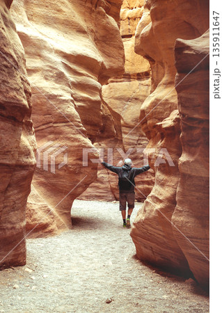 Young man walking in Red Canyon in the Negev Desert near Eilat, Israel Young man walking in Red Canyon in the Negev Desert near Eilat, Israel 135911647