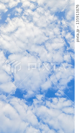Scattered white clouds form a soft pattern across blue sky. Natural light creates even texture without strong contrast. 135913876
