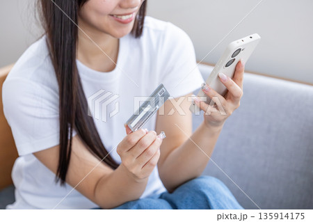 スマホとクレジットカードを持つ若い女性 スマホとクレジットカードを持つ若い女性 135914175
