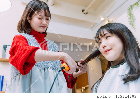 美容院でヘアセットしてもらう女性  若い美容師 135914505
