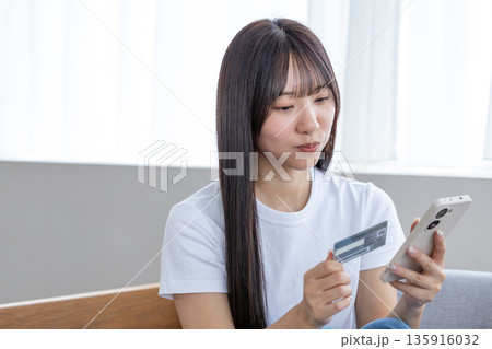 スマホとクレジットカードを持つ若い女性 135916032