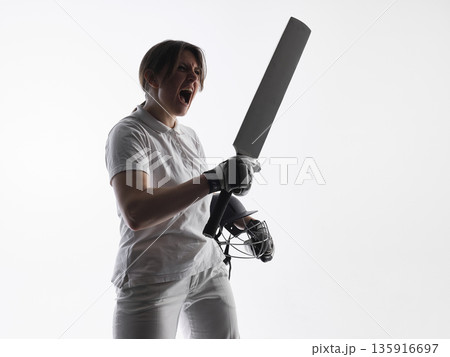 Emotional female cricket player holding bat shouting on white background. Emotional female cricket player holding bat shouting on white background. 135916697