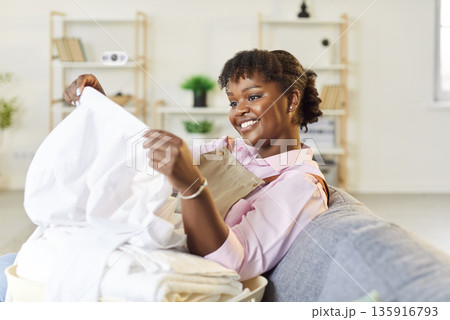Happy African American Woman Doing Housework And Sorting Clean Laundry 135916793