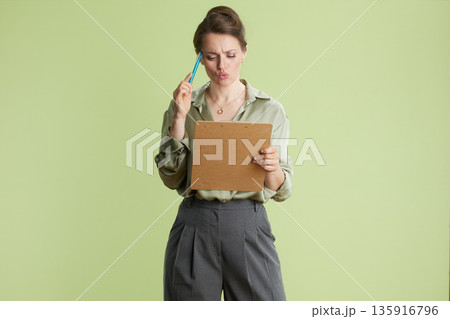 Contemplative businesswoman with clipboard Contemplative businesswoman with clipboard 135916796