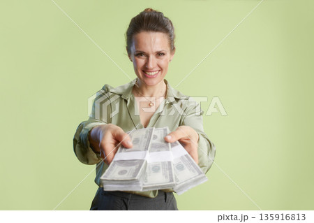 Offering wealth: Woman smiles with stacks of dollars 135916813