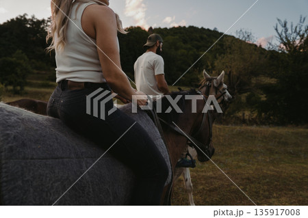 Riding horses at sunset near a forest in the countryside with friends Riding horses at sunset near a forest in the countryside with friends 135917008
