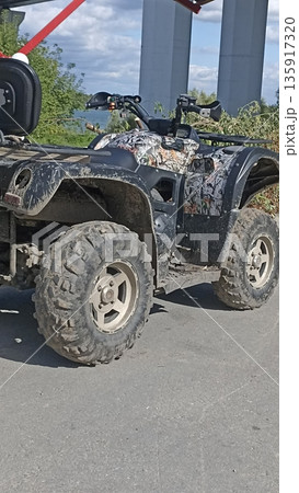 Capture adventure with this camo off-road ATV against a bridge backdrop, ideal for promoting outdoor activities, adventure tourism, and off-road capabilities in recreational settings. 135917320
