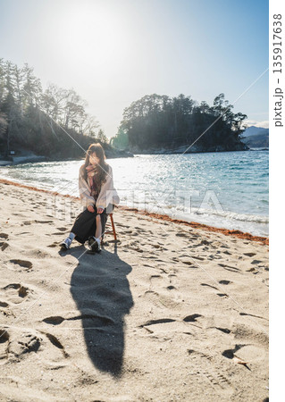 砂浜にある椅子に座る若い女性 砂浜にある椅子に座る若い女性 135917638