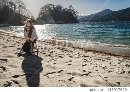 砂浜にある椅子に座る若い女性 135917639