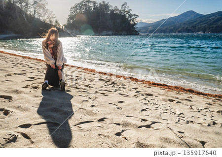 砂浜にある椅子に座る若い女性 135917640