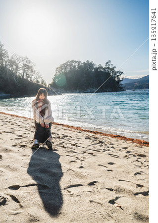 砂浜にある椅子に座る若い女性 砂浜にある椅子に座る若い女性 135917641