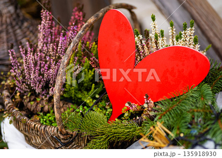 Bright red heart placed among plants and flowers symbolizing love nature harmony and romance 135918930