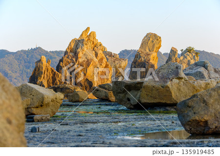 夕日を浴びて黄金色に輝く橋杭岩 135919485