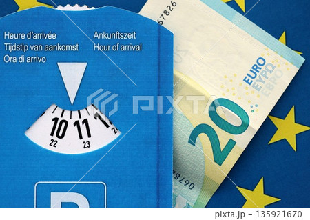 European parking disc with time dial and 20 euro money bill banknote on flag of European Union. Concept of disc parking system in europe European parking disc with time dial and 20 euro money bill banknote on flag of European Union. Concept of disc parking system in europe 135921670