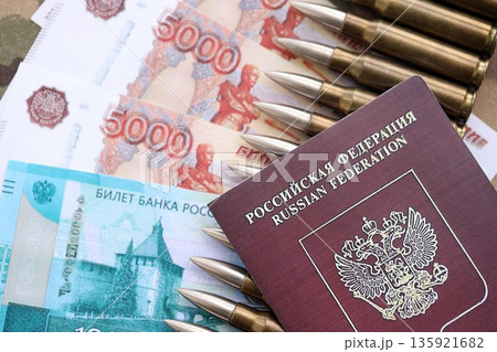 Russian money with bullets on passport and multicam camouflage fabric close up. Concept of russian army funds and invasion to Ukraine 135921682