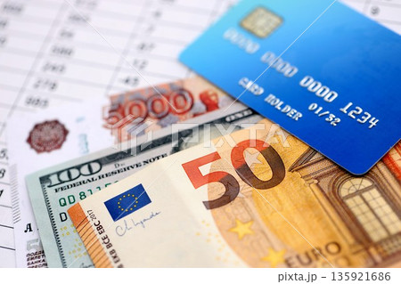 Credit card and russian rubles, euro and US dollar bills banknotes on calculations document background. Currency exchange online and convertations concept Credit card and russian rubles, euro and US dollar bills banknotes on calculations document background. Currency exchange online and convertations concept 135921686