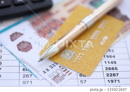 Credit card and pen with russian ruble currency money bills banknotes on calculations document background. Business, financial operations and accounting in Russian Federation Credit card and pen with russian ruble currency money bills banknotes on calculations document background. Business, financial operations and accounting in Russian Federation 135921687