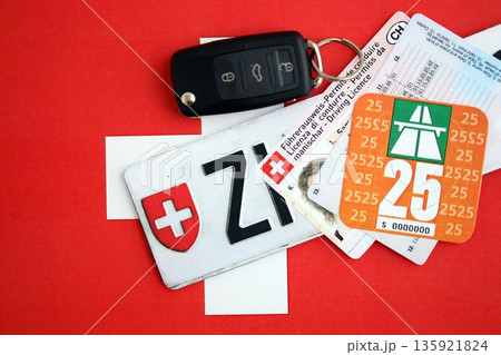 Switzerland vignette sticker for 2025 year and license plate with ignition key on Swiss flag close up. Driving permit and registration concept 135921824