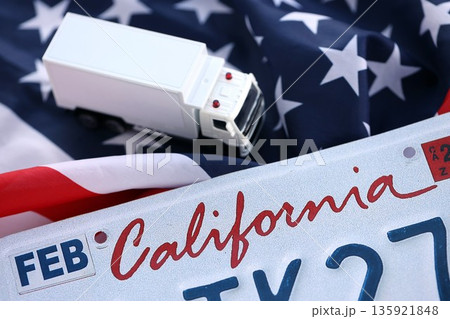 Toy truck and USA state of California license plate on US flag. Concept of driving in California. Reaching a driving permit 135921848