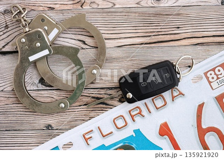 Remote control car keys on Florida license plate and handcuffs. Concept of car accident in Florida. Breaking the law 135921920