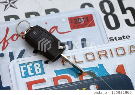 Remote control car keys on US license plates with state names close up. Concept of driving in United States. Reaching a car registration 135921960