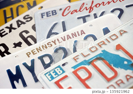 Old US car license plates with various state names close up. Concept of driving in United States. Reaching a car registration Old US car license plates with various state names close up. Concept of driving in United States. Reaching a car registration 135921962