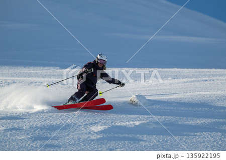 Skier carving fresh powder on a bright mountain slope during a winter sports session 135922195