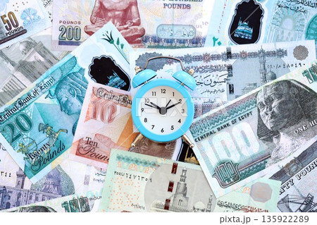 Egyptian pound currency money bills and alarm clock close up. The concept of time management and income Egyptian pound currency money bills and alarm clock close up. The concept of time management and income 135922289