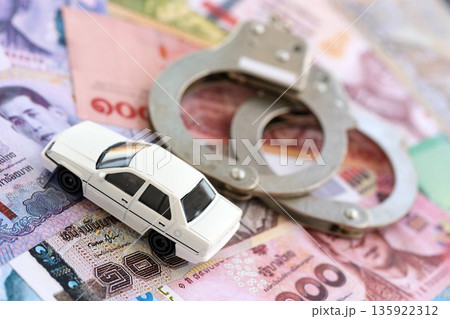 Thai baht currency money bills and toy car with handcuffs close up. The concept of car accident 135922312