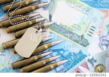 Bahraini dinar currency money bills and rifle bullets with dogtag close up. The concept of warfare and army service Bahraini dinar currency money bills and rifle bullets with dogtag close up. The concept of warfare and army service 135922341